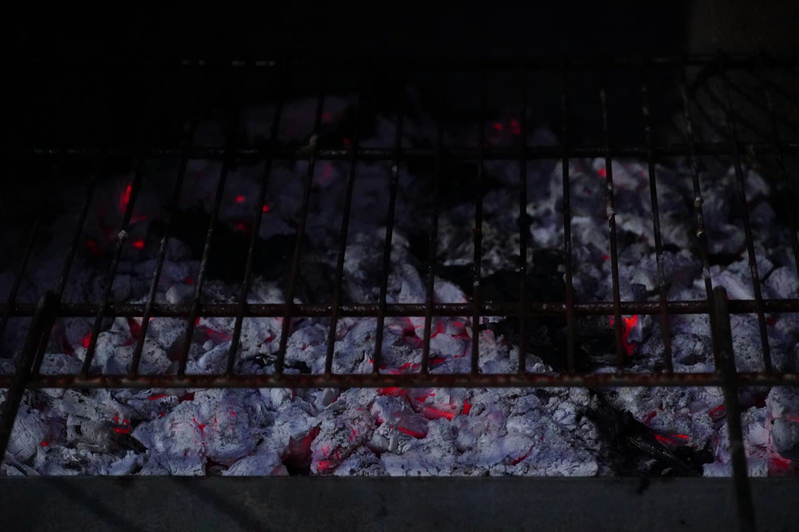 Smoldering charcoal embers glowing under a grill grate